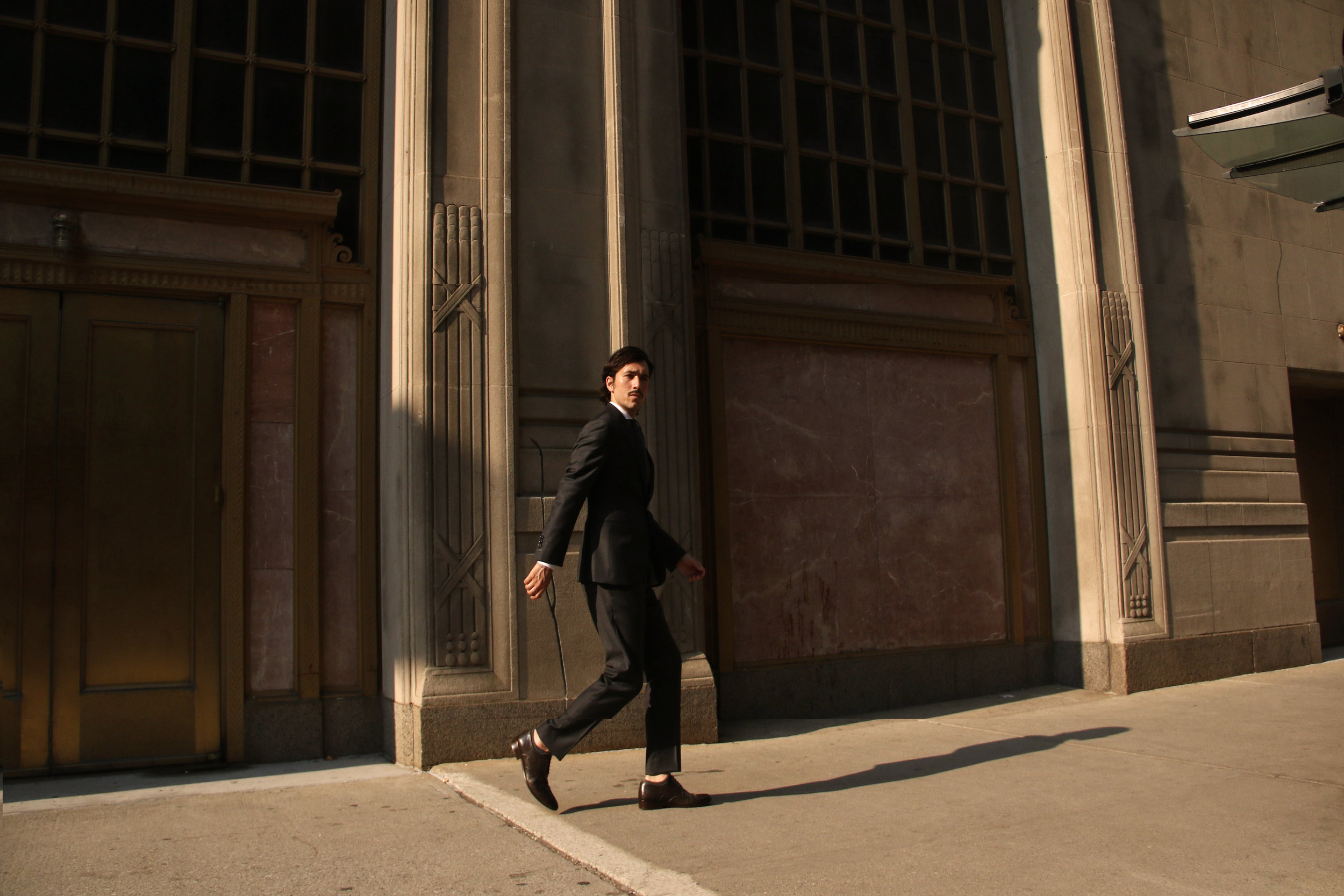 Man in a tailored suit walking past a Chicago stone building